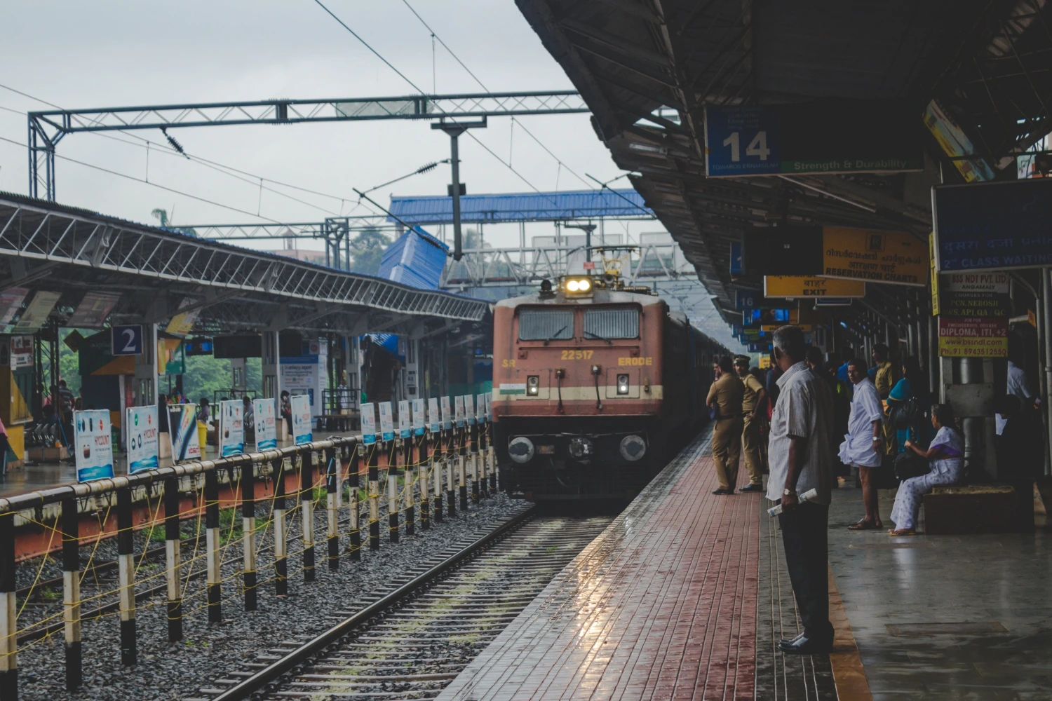 Indian railway train arriving at a busy station platform with passengers waiting