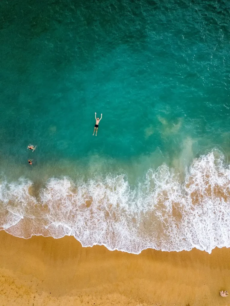 Aerial view of swimmers in the turquoise water at Unawatuna Beach, Sri Lanka